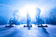 Spinning Instructors On Stage,  Before A Group Of People Doing Spinning On Cycle Bike