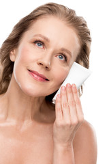 Wall Mural - beautiful mature woman with perfect skin holding moisturizing Face cream Isolated On White