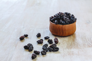 Wall Mural - Dark blue raisins in a wooden bowl on a bright white background. Close-up. Insulated.