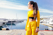 © Rithor - Beautiful young girl in a stylish yellow suit admires a beautiful sea view and a blue sky on a sunny summer day while traveling in a warm country. Travel and inspiration concept