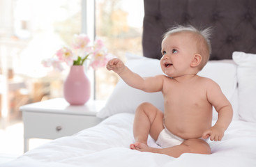 Poster - Cute baby in diaper on bed at home. Space for text