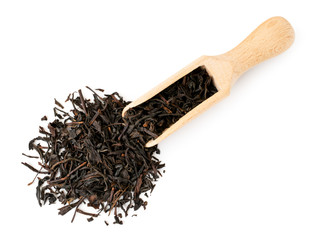 Dried black tea leaves spilled from a wooden spoon on a white. The form of the top.