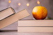 Jabłko leżące na książkach na szarym tle ze światełkami