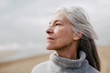 © Bonninstudio/Stocksy - Senior woman enjoying on the beach in winter.