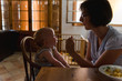 © L?a Jones/Stocksy - Mom giving food to baby on warm summer afternoon