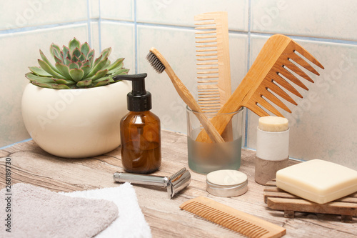Zero waste bathroom accessories, metal safety razor, wooden comb, deodorant, shea butter, solid soap, wooden toothbrush, olive oil make up remover in a glass container, nail brush, aloe vera.