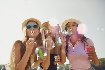 Girlfriends  blowing soap bubbles on the beach.