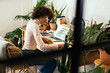 © Bonninstudio/Stocksy - Afro businesswoman working in office full of plants.