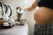 © Ira Efremova Photography/Stocksy - Pregnant woman in her pajamas making coffee