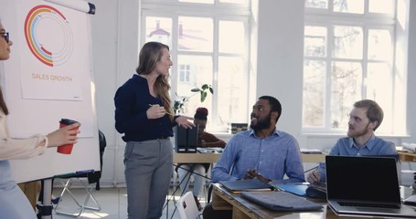 Sticker - Positive young charismatic business woman sharing experience with multiracial colleagues at modern office conference.