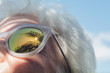 © Kristin Duvall/Stocksy - Senior woman with palm trees reflected in sunglasses