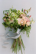 Overgrown Wildflower Bouquet With Grey Silk Ribbon Against A Grey Linen Backdrop