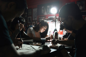 Group of professionals tottooers designing tattoos in studio