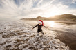 © Cavan Images - Toddler boy wearing red hat splashing in waves at beach at dusk