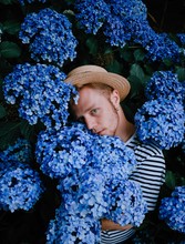 Young Man Standing Amidst Lilac Hydrangea Flowers