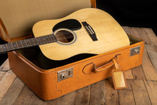 Classical Guitar And Suitcase On A Dark Wooden Table. Stringed Musical Instrument On The Go.