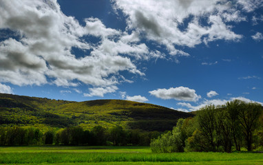 A landscape with mountains and blue sky with white clouds