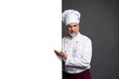 © opolja - Portrait of a happy mature chef cook showing copyspace on the palms isolated on black background.