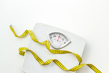 bathroom scales and measuring tape for weight loss concept on white background top view