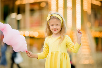 happy child girl with cotton candy at an amusement Park. the concept of the international children's day. happy healthy child in the summer