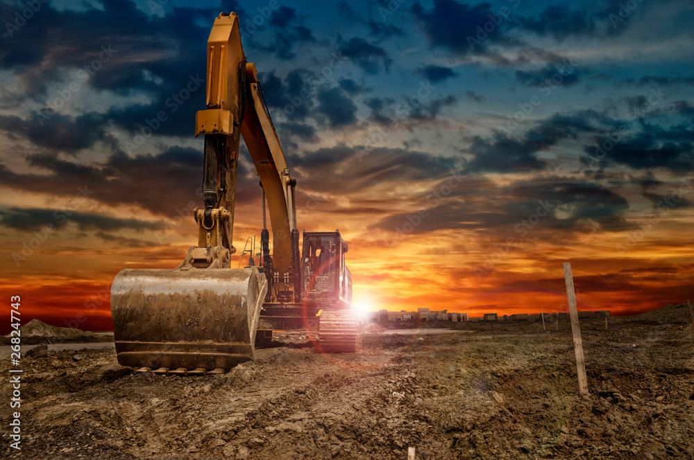 Excavating machinery at the construction site, sunset in background. - obrazy, fototapety, plakaty 