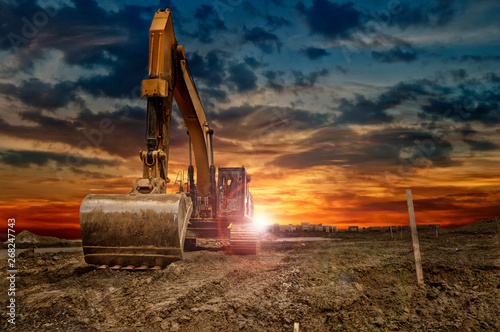 Fotografía Excavating machinery at the construction site, sunset in background