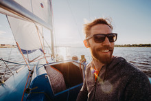 A Handsome Bearded Man In Sunglasses On A Boat On A River Or Lake. Beautiful Happy Guy Swimming In A Boat On A Autumn Sunny Day Feeling Free Enjoying Life
