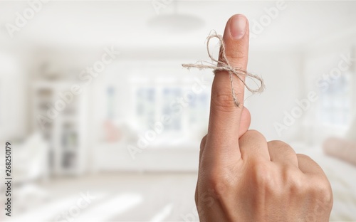 Cuadros en Lienzo Rope bow on finger pointing up on background