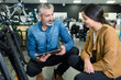 © auremar - bicycle store vendor holding tablet conversing to client