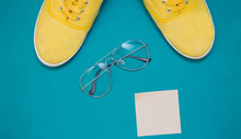 Yellow Sneakers, Glasses  And Sticker On A Green Background