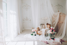 Vintage Armchair Decorated With Peonies  Flowers And Greens, Stands In A Classic Room On A White Wooden Floor Surrounded By Candles Near Large Window And Curtains