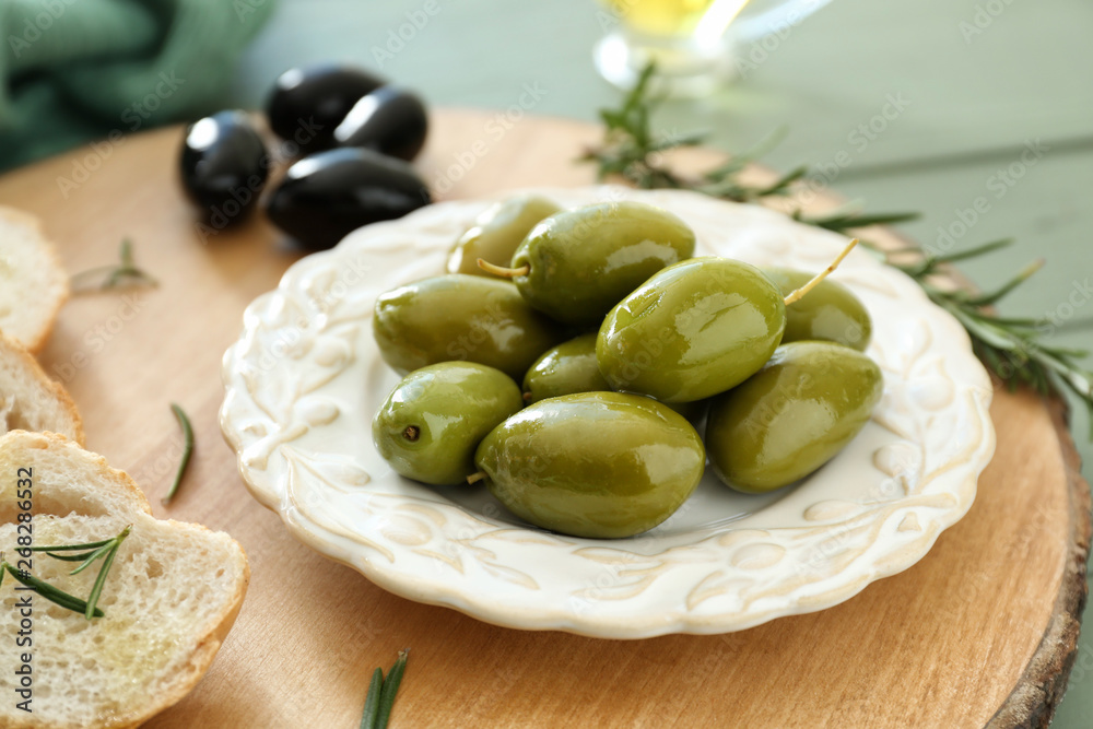 Tasty olives with bread on wooden board, closeup