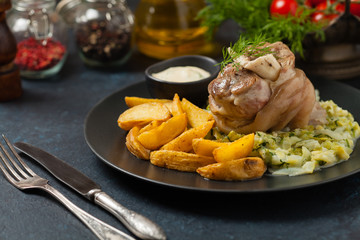 Wall Mural - Boiled knuckle, served with cabbage and baked potatoes. Front view. Darkblue background. Dark mod.