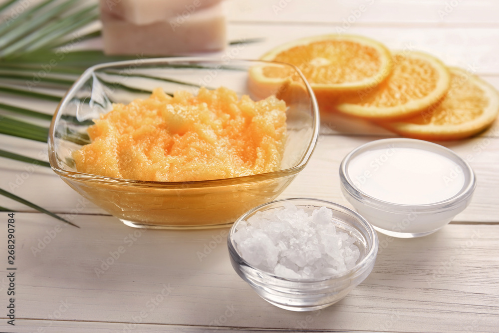 Bowl with body scrub and ingredients on table