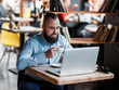 © Ilnur - Young serious bearded businessman working on computer at table,drinking coffee.Man analyzes information, data, develops business plan. Freelancer, entrepreneur.Online marketing, education, e-learning