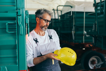 engineer standing beside truck trailer and looking at his hard hat