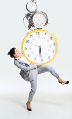 Young woman can't organize her worktime. Forced to constantly stay and work longer. Holding the big clock, has no time. Concept of office worker's troubles, business or problems with mental health.