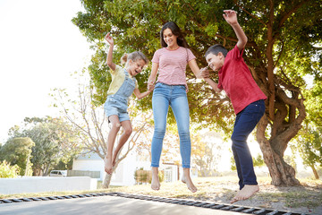 Wall Mural - Siblings With Teenage Sister Playing On Outdoor Trampoline In Garden