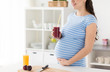 © Syda Productions - healthy eating, pregnancy and people concept - pregnant woman drinking fruit smoothie at home kitchen
