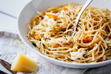 Quick and delicious italian pasta spaghetti with fried eggs, pangrattato and grated parmesan on white plate close-up.Fresh homemade food. Italian healthy food concept.Horizontal orientation