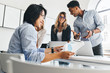 © Look! - Glad asian guy in blue shirt holding documents and smiling while his colleagues joking on background. Indoor portrait of young international co-workers spending time together in office.