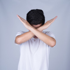 Portrait handsome young asian man wearing a white T-shirt makes X shape or stop sign isolated on grey background. Asian man people. business success concept.