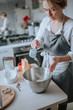 © Irina Polonina - A middle aged woman pastry chef or baker preparing a cake and puts flour in a bowl.
