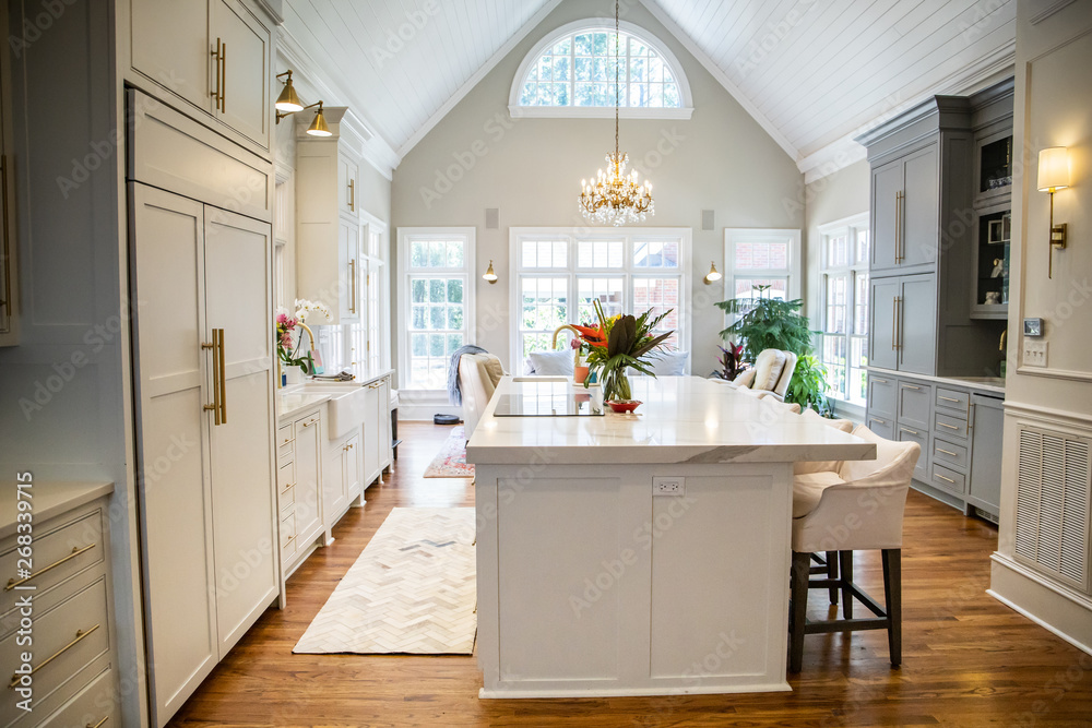 Open Concept Elegant and Spacious Kitchen with Marble Countertops, Chandelier, and Two Toned Cabinets