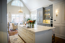 Open Concept Elegant And Spacious Kitchen With Marble Countertops, Chandelier, And Two Toned Cabinets