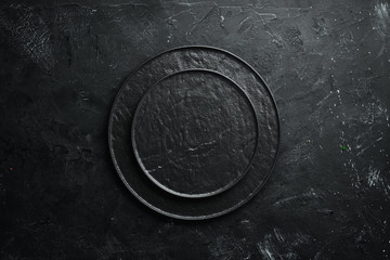 Wall Mural - Round black stone plate. On a black stone background. Top view. Free space for your text.