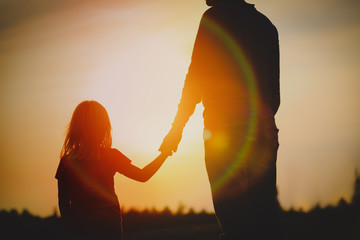 Poster - silhouette of little girl holding parent hand at sunset