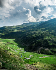 River meadows with green grass and mountains in background