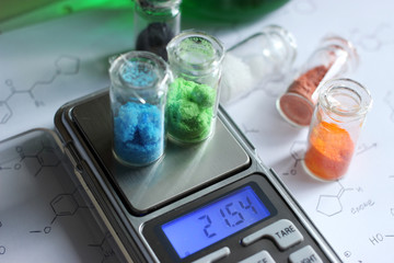 Weighing chemicals on an electronic balance, copper sulfate and nickel sulfate salts, and mass values in grams.