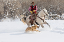 Cowboy Rides Horse Through Snow While Dog Runs Alongside